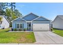 Desirable single-story home boasts a manicured lawn, two-car garage, tasteful landscaping, and classic blue siding at 361 Rycola Circle, Myrtle Beach, SC 29575
