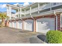 Close-up of condo garages, featuring brick accents and multiple white doors, adding convenient parking at 4827 Orchid Way # 301, Myrtle Beach, SC 29577