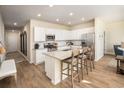 Spacious kitchen with white cabinets, stainless steel appliances, an island with seating, and hardwood floors at 247 Warner Crossing Way, Loris, SC 29569