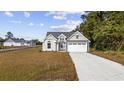 Charming, two-story home with white siding, a two-car garage, and a long concrete driveway at 1892 Blue Bird Rd., Loris, SC 29569