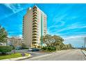 A high-rise condominium building is surrounded by lush landscaping and a parking lot at 210 75Th Ave. N # 4034, Myrtle Beach, SC 29572