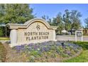 Entrance to North Beach Plantation with stone sign, a landscaped flower bed, and a small sign for the real estate office at 4850 Cantor Ct. # 202, North Myrtle Beach, SC 29582