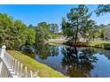 Scenic pond view with a white picket fence and lush greenery in the background at 615 Woodbine Ct., Myrtle Beach, SC 29579