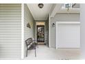 Cozy front porch featuring a welcoming bench, decorative accents, and covered entry adjacent to the garage at 129 Astoria Park Loop, Conway, SC 29526