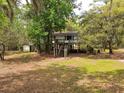 Exterior view of elevated home with wooden stairs and porch, surrounded by trees and grass at 1030 Waccamaw Lake Dr., Conway, SC 29526