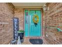 Inviting front entry featuring a teal door, brick facade, and cheerful welcome decor at 1421 Cottesmore Ct., North Myrtle Beach, SC 29582