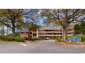 Three-story exterior shows lush landscaping, designated parking, and a sign for Arrowhead Court at 180 Rothbury Circle # 203, Myrtle Beach, SC 29572