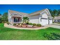Well-manicured home exterior featuring a brick accent wall, lush landscaping, and an attached garage at 204 Rosewater Loop, Myrtle Beach, SC 29588
