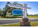 Entrance sign for Meadows Edge community, set against a backdrop of lush green fields and a clear blue sky at 319 Myrtle Meadows Dr # 401D, Conway, SC 29526