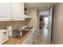 A compact kitchen featuring white cabinets, an oven, a stainless steel sink, and tile floors at 201 75Th Ave N # 4065, Myrtle Beach, SC 29572