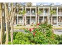 View of the townhouse exterior with lush landscaping with red flowers, palm trees, and a parking area at 2790 Howard Ave. # D, Myrtle Beach, SC 29577