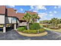 Landscaped townhouse featuring well-manicured lawn, mature palm trees, and a spacious driveway at 12 Spartina Ct. # 2, Pawleys Island, SC 29585