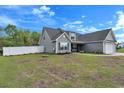 Rear exterior view of a charming one-story home with gray siding and a large backyard with a white fence at 1794 Graham Rd., Aynor, SC 29544