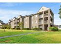 A multi-story condo building with multiple units, balconies, and landscaped lawn at 380 Myrtle Greens Dr. # D, Conway, SC 29526