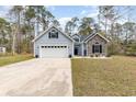 Charming home featuring a two-car garage, stone accents, and complemented by a beautifully landscaped front yard at 480 N Boundaryline Dr. Nw, Calabash, NC 28467