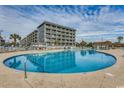 Beautiful community pool with lounge chairs, umbrellas, and building in background at 5905 S Kings Hwy. # A551, Myrtle Beach, SC 29575