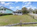 Spacious front yard view of cozy single story home with a large lawn and a quaint fence at 600 Hillside Dr. S, North Myrtle Beach, SC 29582