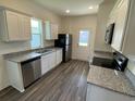 Modern kitchen with white cabinets, stainless steel appliances, and granite countertops with a view to the backyard at 615 Muster Field Ct., Conway, SC 29526