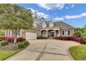 Lovely brick home featuring a paved driveway, beautiful landscaping, and a two-car garage at 9278 Nw Checkerberry Square, Calabash, NC 28467