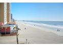 Scenic view of a sandy beach with building amenities and a distant pier at 9540 Shore Dr. # 3-H, Myrtle Beach, SC 29572