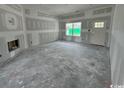 Spacious, unfinished living room with a fireplace and large windows that provide natural light at 384 William Nobles Rd., Aynor, SC 29511