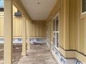 A covered porch with a smooth, gray concrete floor, yellow siding, and white pillar accents at 804 Edisto Ct., Myrtle Beach, SC 29588
