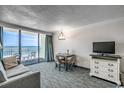 Bright living room with ocean view, dining table, sofa, and tv; perfect for relaxing and entertaining at 1105 S Ocean Blvd. # 502, Myrtle Beach, SC 29577
