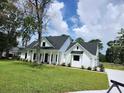 Beautifully landscaped new construction home featuring a covered porch, black framed windows, and a large yard at 1464 Hawthorn Dr., Pawleys Island, SC 29585