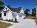 Three car garage boasts white doors, contrasting trim and a large concrete driveway and is surrounded by landscaping at 1464 Hawthorn Dr., Pawleys Island, SC 29585
