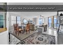 Bright living room features a dining area and ocean views from windows and balcony access at 1690 N Waccamaw Dr. # 1008, Garden City Beach, SC 29576