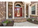 Inviting front porch with brick columns, colorful chairs, decorative plants, and attractive front door at 2039 Woodburn Dr., Myrtle Beach, SC 29579