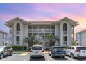 Condo building with parking, showcasing a well-maintained facade and lush landscaping with palm trees at 4409 Eastport Blvd. # E2, Little River, SC 29566