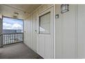 Unit 401 entrance with a white door, storm door, exterior carpet, and outside lighting at 811 N Ocean Blvd. # 401, Surfside Beach, SC 29575