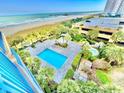 Scenic aerial view showcasing a blue swimming pool and lush landscaping near the beach at 8560 Queensway Blvd. # 304, Myrtle Beach, SC 29572