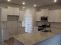 Modern kitchen with white cabinets, granite countertops, and stainless steel appliances at 8723 Baton Rouge Ave Nw, Calabash, NC 28467