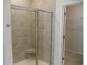 Tiled shower with glass door and a built-in seat, adjacent to a walk-in closet at 8743 Baton Rouge Ave Nw, Calabash, NC 28467