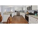 Modern kitchen with stainless steel appliances, granite countertops, white cabinetry, and hardwood floors at 1114 S Dogwood Dr., Surfside Beach, SC 29575