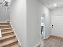 Bright hallway featuring a staircase with tan carpet, white walls, and a doorway leading to a dining area at 1223 American Shad Dr. # 42, Conway, SC 29526