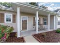 Inviting front porch with rocking chairs, decorative columns, and landscaped flowerbeds enhance curb appeal at 180 Oak Crest Circle, Longs, SC 29568