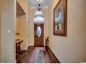 Inviting foyer with hardwood floors, an elegant chandelier, and an arched transom window above the front door at 8261 Timber Ridge Rd., Conway, SC 29526