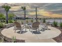 Outdoor fire pit surrounded by comfortable seating, landscaping, and swaying palm trees near a scenic pond at 281 Hawks Run Dr., Calabash, NC 28467