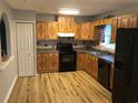 Well-lit kitchen features wood cabinetry, black appliances, and modern flooring at 4204 Peachtree Ln., Myrtle Beach, SC 29588