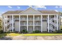 Inviting condo complex featuring multiple stories, white railings, and well-maintained landscaping under a clear sky at 5882 Longwood Dr. # 201, Murrells Inlet, SC 29576