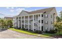 Multi-story condominium showcasing spacious balconies, white railings, green shutters, and convenient parking at 5882 Longwood Dr. # 201, Murrells Inlet, SC 29576