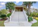 Grand staircase ascends to covered porch and entrance, surrounded by palm trees and lush landscaping at 9 Gasparilla Circle, Murrells Inlet, SC 29576