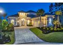 Elegant home featuring a tiled roof, beautiful landscaping and lighting, and paver driveway at 9407 Venezia Circle, Myrtle Beach, SC 29579