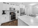 Modern kitchen features white cabinets, stainless steel appliances, marble countertops, and dark wood flooring at 115 Foxford Dr., Conway, SC 29526