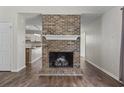 Open living room with a striking brick fireplace and modern wood floors at 1406 Snowy Egret Dr., Murrells Inlet, SC 29576