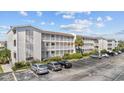 Low-angle view of a multi-story condo with white balconies, lush landscaping, and ample parking space at 1919 Spring St. # 36A, North Myrtle Beach, SC 29582