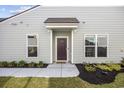Close-up view of the front door, complemented by neat landscaping and symmetrical window placement at 6562 Torino Lane, Myrtle Beach, SC 29572